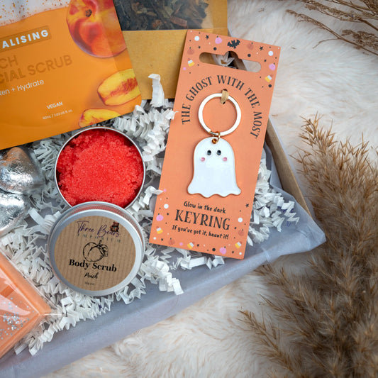 Glow-in-the-dark ghost keyring with body scrub and other items on a textured surface