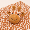 A plush giraffe toy resting on a soft blanket with a matching giraffe print pattern, photographed against a plain light background.
