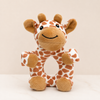 A plush giraffe baby teether toy with a soft brown and white pattern, sitting upright on a light surface against a warm beige background.