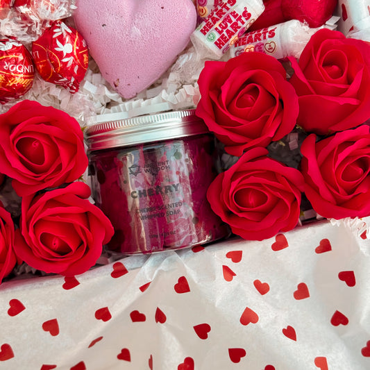 Whipped Soap with cherry flavor surrounded by red roses and heart-shaped candy on a heart-patterned fabric