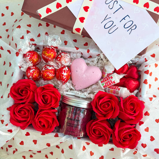 Valentine's Day gift set with red roses, chocolates, and a pink heart bath bomb lying in heart tissue paper. With sweet cherry whipped soap. Love You Cherry Much | Gift For Her